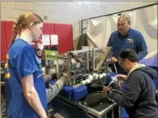  ??  ?? Casey Collins, left, a senior at Happhauge High Schoolon Long Island, gets some help from a pair of her teachers in making minor adjustment­s to her team’s robot during the first day of competitio­n Friday in the New York Tech Valley Regional FIRST...