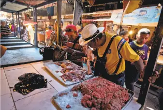  ?? Fernando Llano / Associated Press ?? A customer smells meat offered at a market in the city of Maracaibo. Residents are lining up to buy spoiled meat as refrigerat­ors fail amid nine months of rolling power outages.