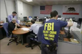  ?? ERIC RISBERG — THE ASSOCIATED PRESS ?? Oakland police detectives and FBI agents work together in the offices of the Oakland Safe Streets Task Force in Oakland Standing at left is Oakland homicide detective Jason Turner. The federal government already plays a big role in fighting violent...