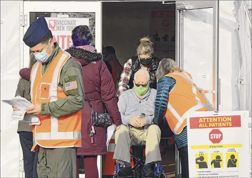  ?? Lori Van Buren / Times Union ?? A man in a wheelchair is brought into a tent on Friday to receive a COVID-19 vaccine at the University at Albany in Albany.