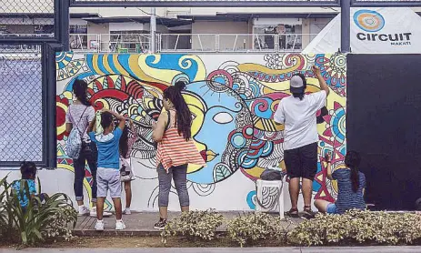  ??  ?? Pedestrian art: At Circuit Makati, a black and white mural by a local artist is filled in by kids and parents using paints and brushes supplied by Ayala Land.