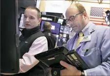  ?? Richard Drew/Associated Press ?? Trader Peter Mancuso, right, works on the floor of the New York Stock Exchange on Thursday as oil prices continued to drop and energy companies took sharp losses.