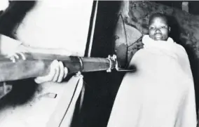  ?? ?? A member of the Mau Mau, wrapped in the blanket in which he was sleeping, is held at gun point during a round-up at 2:30 am by the Fifth Battalion King’s African Rifles in the Nyeri district of Kenya on November 13, 1952. Several prisoners were taken, including teachers at the Jomo Kenyatta-sponsored Mungari School where they were accused of spreading Mau Mau doctrines to the pupils. The man in this picture was arrested for being in the possession of subversive literature.