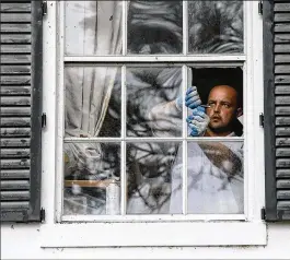  ?? BRUCE R. BENNETT / THE PALM BEACH POST ?? Robert Lisboa of Best Glass Guys repairs damage to window panes at Mary Burgio’s home on Apache Boulevard. In addition, siding was torn from her shed and a cover for her water system was tossed down the street.