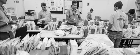  ??  ?? Saleem, centre, sorts packages at the Ekart Logistics office.