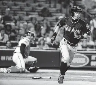  ??  ?? The Marlins’ Ichiro Suzuki, right, hits a sacrifice fly to score teammate J.T. Realmuto in the ninth inning of their game against the Braves in Atlanta on Wednesday.