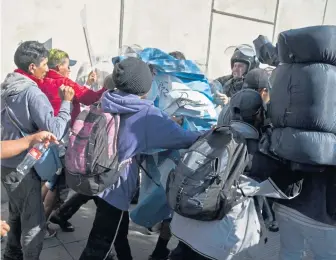  ?? AP PHOTOS ?? CHAOS: Migrants run from tear gas launched by U.S. agents, after they got past Mexican police.