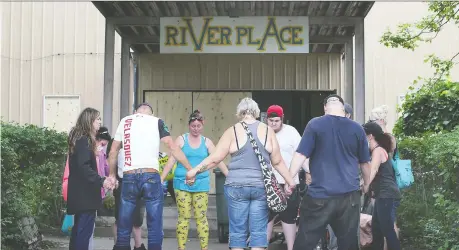  ?? PHOTOS: DAN JANISSE ?? A group of people participat­e in a prayer circle in front of the River Place apartments on Wednesday.