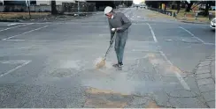  ?? Picture: Thapelo Morebudi ?? Thabang Molefe sweeps soil into potholes on Reitz and Van Velden streets in Brits, part of the Madibeng local municipali­ty in the North West.