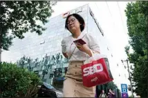  ?? (AP) ?? A woman passes by the Didi headquarte­rs in Beijing on July 16, 2021. Chinese regulators have ordered ride-hailing platforms to correct unfair market tactics amid a crackdown on the internet sector that has spooked investors and shaved billions off the valuations of some of China’s biggest technology companies.