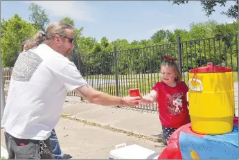  ?? RACHEL DICKERSON/MCDONALD COUNTY PRESS ?? Customer Tim Hannon gets a cup of lemonade from Ryleigh Gilliam on Main Street in Noel. She set up a lemonade stand on May 30 to benefit the McDonald County Senior Center and raised $201, much of which was donations.