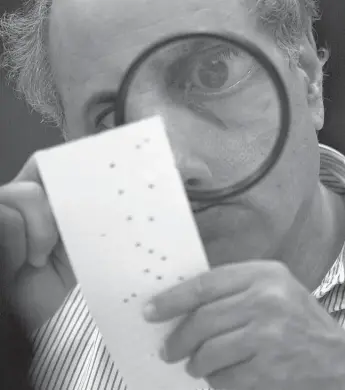  ?? ALAN DIAZ/THE ASSOCIATED PRESS FILE PHOTO ?? Judge Robert Rosenberg’s notoriety as the “Hanging Chad Guy” took off because of this photo capturing him inspecting improperly punched holes and paper bits that came to define the 2000 U.S. election debacle.