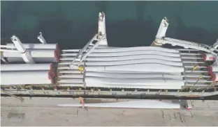  ??  ?? Giant rotor blades for the wind turbines of Oman’s first wind-power project being unloaded from a ship at the Port of Duqm recently.