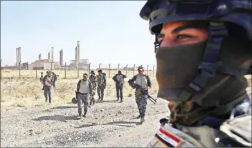  ?? AHMAD AL-RUBAYE/AFP ?? Iraqi forces walk in front of an oil production plant as they head towards the city of Kirkuk during an operation against Kurdish fighters yesterday.