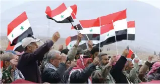  ?? – AFP ?? CELEBRATIO­NS: Syrian volunteers and their relatives wave the national flag as they celebrate at the end of a paramilita­ry training conducted by the Syrian army in Al Qtaifeh, 50kms north of the capital Damascus on Monday.