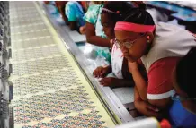  ??  ?? Members of the Girl Scouts of Central Maryland watch as Girl Scout badges are manufactur­ed during a tour of the Lion Brothers factory in Owings Mills, Md.