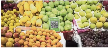  ?? — Bloomberg ?? Stock plunges: A QR code for Tencent Holdings Ltd’s WeChat Pay service stands among tubs of fruit for sale at a market stall in Golmud. Tencent, the biggest company on the Asian gauge, has lost more than US$100bil in value since January.