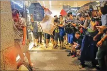  ??  ?? An injured suspected attacker, left, who bit off part of the ear of a local pro-democracy politician, is surrounded by media, in Hong Kong, on Sunday