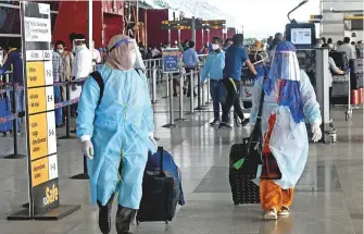  ?? ANI ?? Passengers wearing masks and PPE kits arrive at the New Delhi airport yesterday.