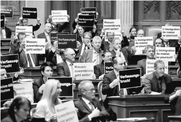  ??  ?? National Councilors of the Swiss People’s Party hold posters reading ‘constituti­onal breach’ and ‘mass immigratio­n continues’ after the vote on curbing the immigratio­n, in the parliament in Bern, Switzerlan­d. — Reuters photo