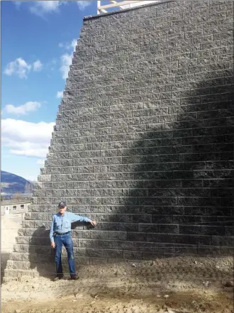  ?? JAMES MILLER/The Okanagan Weekend ?? Hugo Deuschle stands beside a seven-metre wall on the property line at 2764 Cedar Rd. in Penticton. Deuschle said the wall is clearly in violation of city zoning bylaws and wants it torn down.