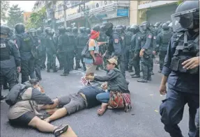  ?? ?? Mujeres ayudan a un hombre mientras la policía impide que otros marchen hacia la sede de la cumbre APEC