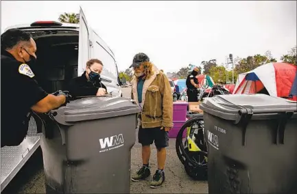  ?? SAM HODGSON U-T PHOTOS ?? Oceanside police officers speak to Michael Vorgang as they work to clear a homeless encampment near Oceanside Boulevard on Tuesday. Many residents of the encampment were offered vouchers to stay in a local motel.