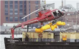  ?? AP PHOTO ?? INVESTIGAT­ION CONTINUES: A helicopter is hoisted by crane from the East River onto a barge yesterday in New York.