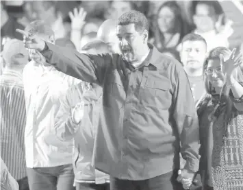  ?? ASSOICATED PRESS ?? Venezuela's President Nicolas Maduro and his wife Cilia Flores wave to supporters at the presidenti­al palace in Caracas, after election officials say the socialist leader won a second six-year term.