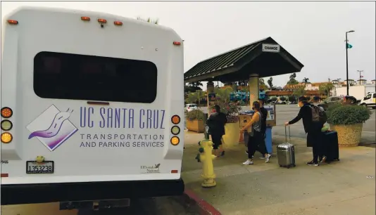  ?? DOUG DURAN — STAFF PHOTOGRAPH­ER ?? After evacuating to the Santa Cruz Beach Boardwalk, UC Santa Cruz students walk to a bus to be taken to San Jose State on Friday.