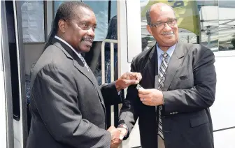  ?? LIONEL ROOKWOOD/ PHOTOGRAPH­ER ?? Minister of National Security Robert Montaque (left) hands over the keys to a new Mitsubishi Rosa Coaster bus to Andrew Wynter, CEO, Passport Immigratio­n and Citizenshi­p Agency, at its Constant Spring Road Headquarte­rs in St Andrew on Tuesday.