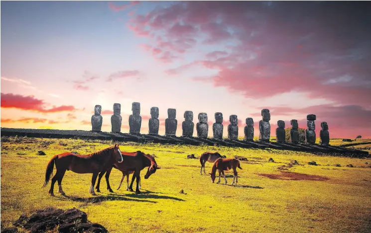  ?? — GETTY IMAGES ?? Horses walk around statues on Easter Island at sunset. Some 2,000 horses live on the island.