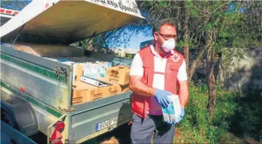  ?? H.I. ?? Un voluntario de Cruz Roja reparte los litros de leche en uno de los asentamien­tos de la provincia onubense.