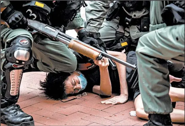  ?? ISAAC LAWRENCE/GETTY-AFP ?? Police arrest pro-democracy protester at gunpoint Sunday in Hong Kong. At least 180 demonstrat­ors were arrested, mostly on charges of unlawful assembly.