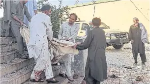  ?? ?? BLOODY FRIDAY: Afghan men carry the dead body of a victim to an ambulance after a bomb attack at a mosque in Kunduz on Friday.