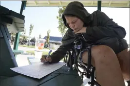  ?? RICH PEDRONCELL­I — THE ASSOCIATED PRESS ?? Elisha McDonald, who's been without a home since February, signs a voter registrati­on form she has just filled out at Loaves and Fishes, a nonprofit facility for the homeless in Sacramento, on Thursday.