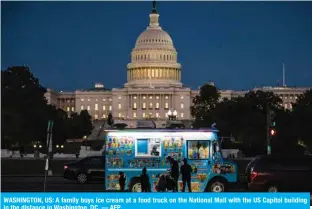  ?? — AFP ?? WASHINGTON, US: A family buys ice cream at a food truck on the National Mall with the US Capitol building in the distance in Washington, DC.