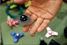  ?? AP PHOTO/CARLOS OSORIO ?? In this May 11 photo, Funky Monkey Toys store owner Tom Jones plays with a f fidget spinner in Oxford, Mich. The mania for fidget spinners, the 3-inch twirling gadgets taking over classrooms and cubicles, is unlike many other toy crazes.