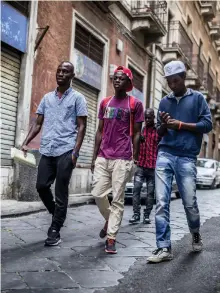  ?? AP ?? Above, from left, refugees Mikailou Diallo, Landing Solly Ameidou Sidy Iraore and Asowe Abdoulie walk through Catania, Sicily, after a visit to a community centre; left, migrants on the Golfo Azzurro arrive at the port of Pozzallo in Sicily after being...