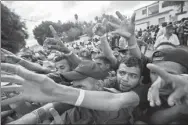  ?? PEDRO PARDO / AFP ?? A crowd of Central American migrants stretch their hands to get food offered by volunteers outside a shelter in Tijuana, Mexico, near the US-Mexico border fence on Saturday.