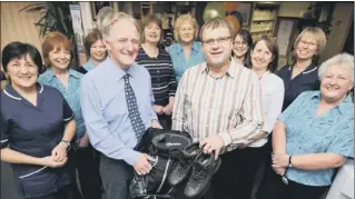  ??  ?? Dr Paul Robinson (front, left) receives his retirement gifts of a rucksack and walking boots from Dr Phil Jones (front, right) watched by fellow doctors, nurses (including his wife Suzan, left) and practice staff 120836a