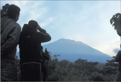  ?? Firdia Lisnawati ?? The Associated Press Villagers watch Bali’s Mount Agung from an observatio­n point about 7.4 miles away from the volcano Thursday in Karangasem, Indonesia. Hundreds of tremors from the mountain are recorded daily, leading scientists to presume an eruption is due.