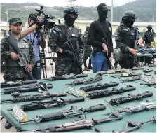  ?? ORLANDO SIERRA/AFP/GETTY IMAGES ?? Police and military personnel display an assortment of assault rifles and ammunition seized from members of the Barrio 18 and Mara Salvatruch­a gangs during a raid last year.