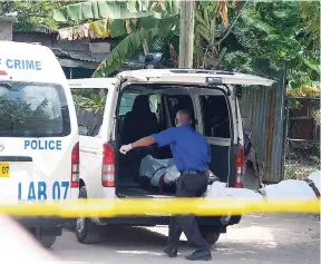  ?? IAN ALLEN/PHOTOGRAPH­ER ?? Employees of a funeral home remove the body of a murder victim from a house in August Town, St Andrew.