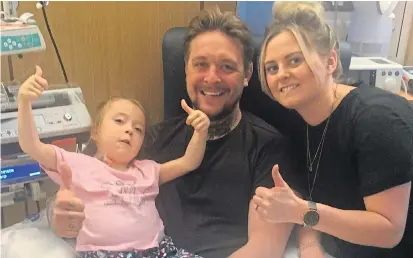  ?? Picture: SWNS ?? Brave Daisy Mason, seven, gives the thumbs-up with parents Adam and Lucy following her treatment