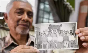  ??  ?? The good old days: Yusof showing a photo of himself (seated, second left) with his friends at the Al-Azhar University at his home in Kerteh, Terengganu. — Bernama