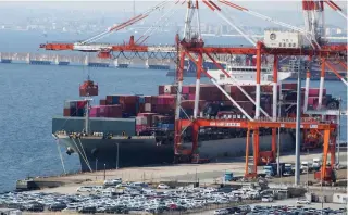  ?? AP PHOTO ?? SURGE
A container ship is loaded and unloaded at a container terminal at a port of Kawasaki near Tokyo on March 9, 2022. Japan’s exports increased nearly 10 percent in December on the back of high demand for vehicles, machinery and computer chips, and the resumption of trade with China.