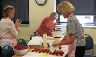  ??  ?? Jan Johnson, left, Barbara Bodmer, center, and Shirley Johnson prepare strawberri­es for dipping during the Kirtland Kiwanis Strawberry Festival on June 18. Going into the day, 1,054 chocolate-dipped strawberri­es were sold.