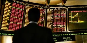  ?? AFP/VNA Photo ?? An investor watches a trading board at the Australian Securities Exchange. Australia's S&P/ASX 200 index lost nearly 0.5 per cent yesterday.