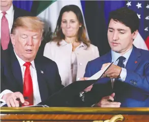  ?? SAUL LOEB / AFP / GETTY IMAGES ?? President Donald Trump and Prime Minister Justin Trudeau put pens to the revamped
free-trade agreement between the U.S., Mexico and Canada in 2018.